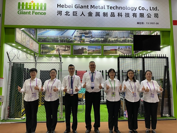 Giant Fence team in formal suits at 140th Canton Fair booth with varied metal fences.