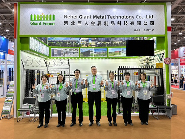 Giant Fence sales team posing at 140th Canton Fair exhibition booth with fence displays.