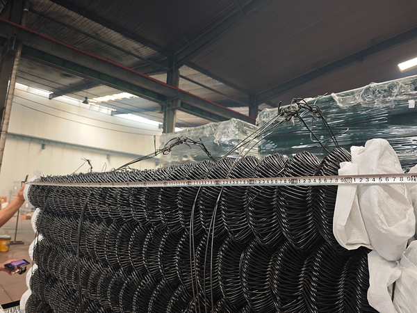 Measuring roll width of bulk chain link fence before shipment in factory.