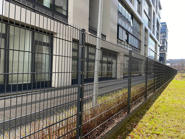 Cerca dobro moderna do fio instalada ao lado dos edifícios do escritório para a segurança do perímetro