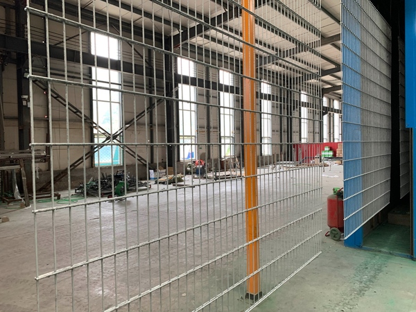 Galvanized 2D fence panel stands upright for inspection inside the workshop.