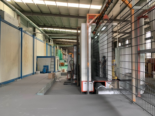 Workers spray coating on 2D fence panels in automatic powder coating line.