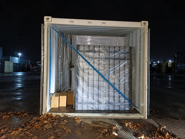 Steel tubular fence packed in plastic film and loaded into shipping container.