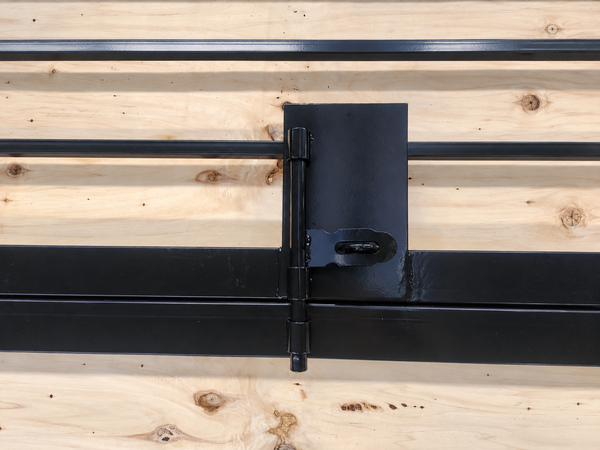 Black steel tubular gate hinge and latch detail on wooden workshop board.