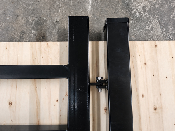 Close-up view of hinge assembly for black steel tubular fence gate posts.