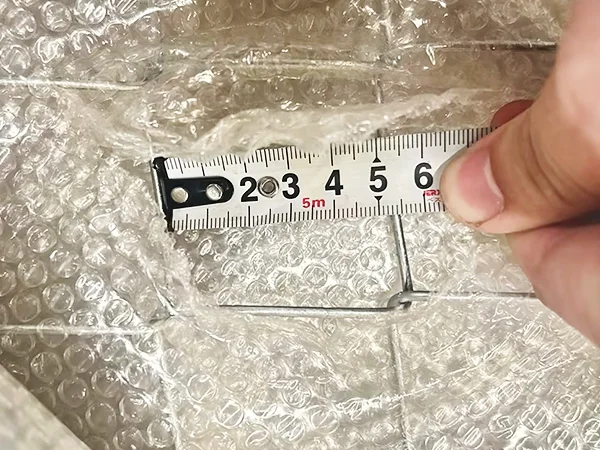 A QC worker is measuring the mesh size of chain link fence.