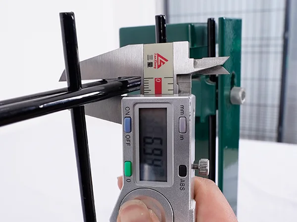 A QC worker is measuring the horizontal wire diameter of 2D fence.