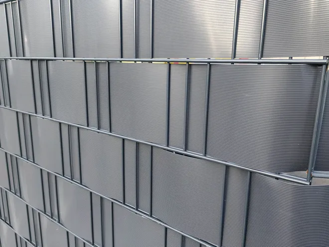2D privacy fence with privacy slats interlaced through the wire mesh.