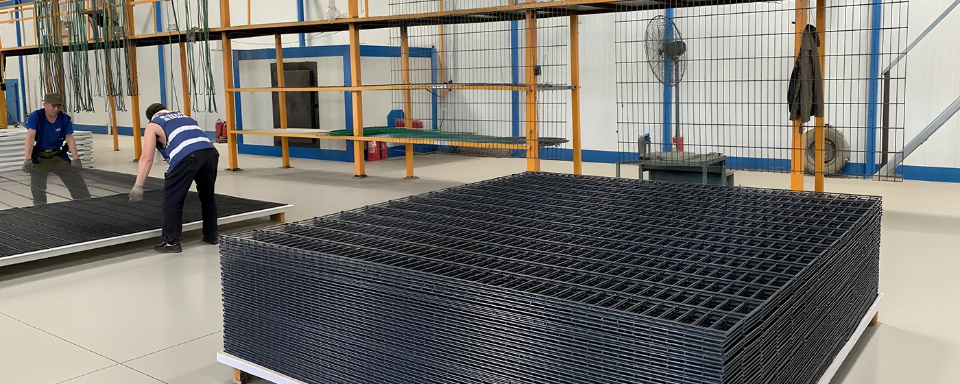 Two workers are unloading the powder coated 2D security fence on the pallet.