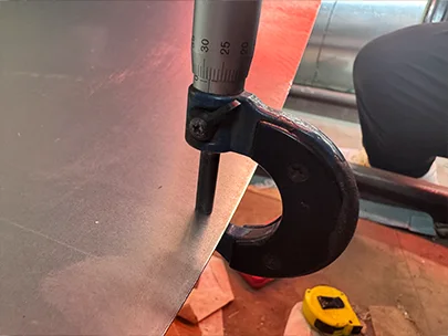 A QC worker is measuring the plate thickness of steel plate.