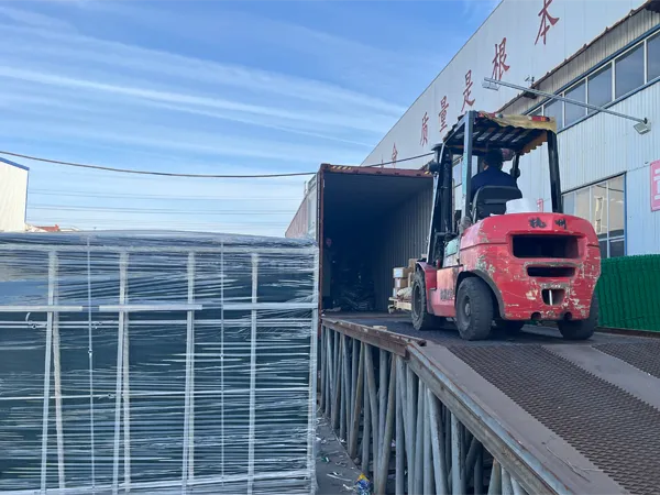 A forklift loads 358 security fence (wrapped) into a container at a factory with quality slogans.
