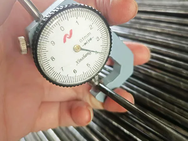 A QC worker is measuring the wire diameter of 358 high security fence.