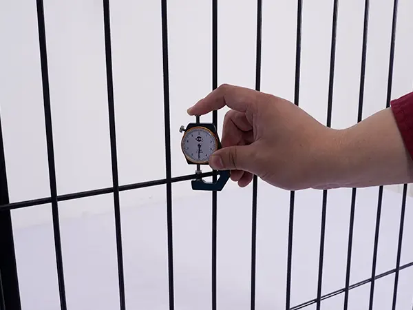 A QC worker is measuring the line wire diameter of 3D fence.