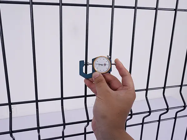 A QC worker is measuring the cross wire diameter of 3D fence.