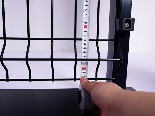 A QC worker is measuring the height of 3D fence.