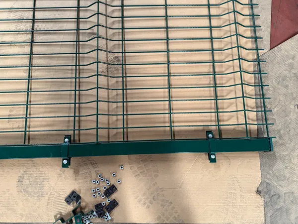 Green 3D welded mesh fence with posts and installation hardware laid flat
