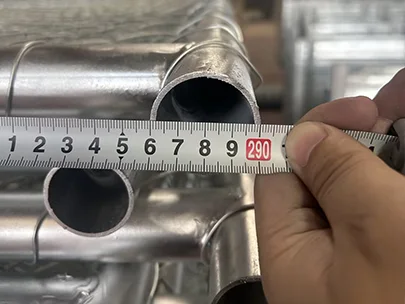 A QC worker is measuring the width of American temporary fence with meter tape.