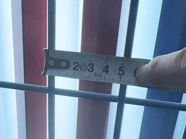 A QC worker is measuring the mesh size of 3D panel type airport fence.