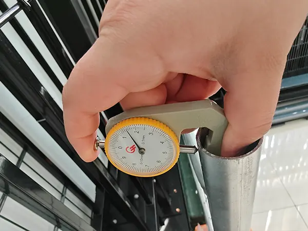 A QC worker is measuring the frame thickness of American temporary chain link fence.
