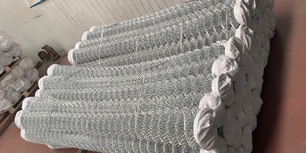 Several rolls of galvanized chain link fences on the ground.