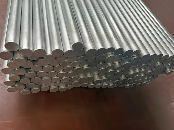 Several pieces of galvanized chain link fence posts on the ground.