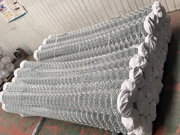 Several rolls of galvanized chain link fences on the ground.