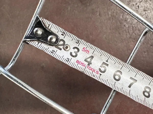 A QC worker is measuring the mesh size of chain link fence.