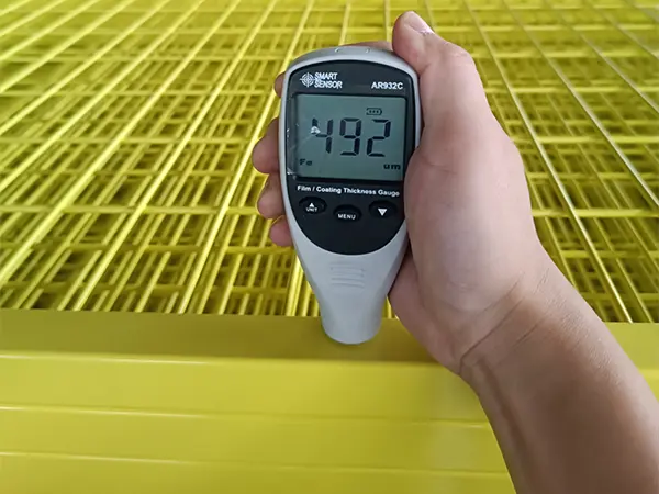 A QC worker is measuring the coating thickness of Canada temporary fence.