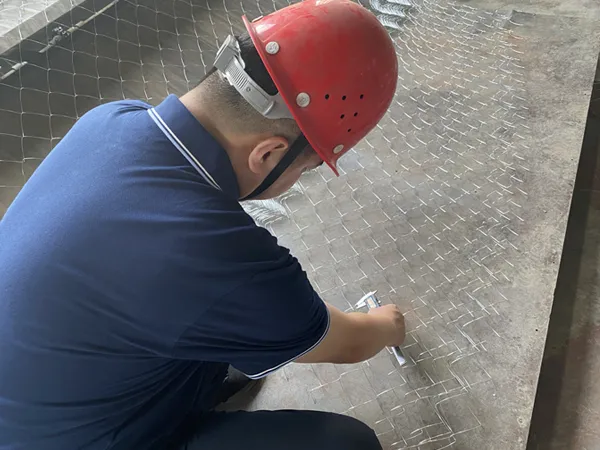 A worker is checking chain link fence with a testing tool.