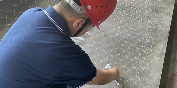 Un travailleur vérifie clôture de maillon de chaîne avec un outil de test.