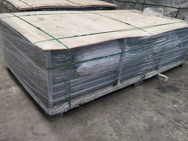 A metal pallets of chain link fence post on the ground.