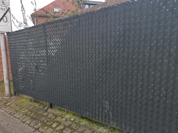 Chain link fence with dark privacy tape installed along a residential boundary.