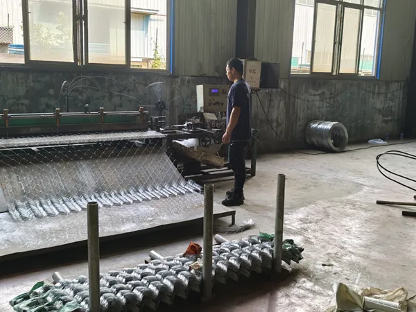 A worker is producing chain link fence.