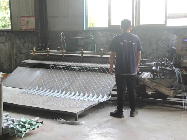 A worker is producing chain link fence.