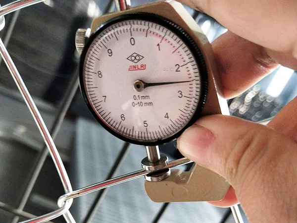 A QC worker is measuring the wire diameter of chain link fence.