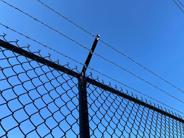 Barbed wire is installed on top of the black chain link fencing system for enhanced security.
