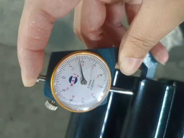 A dial gauge measures the thickness of the coated wire for chain link fencing system.