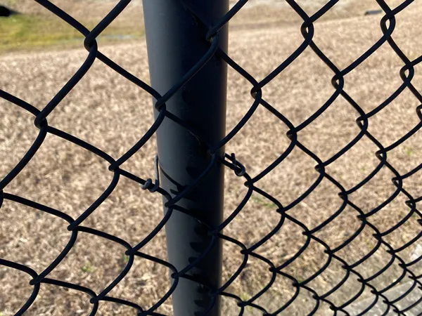 Close-up of the connection detail of the black chain link fencing system mesh and post.