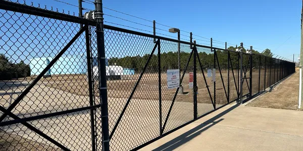 Full view of a black chain link fencing system perimeter protecting an industrial water site.