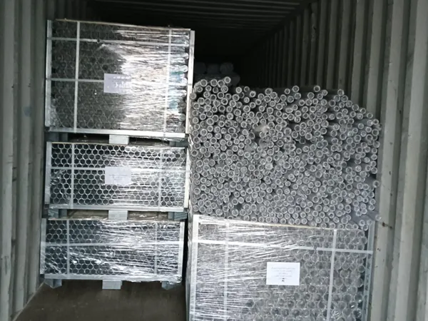 Galvanized chain link fencing system parts are packed and loaded into a shipping container for export.