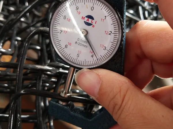 The dial gauge shows the wire diameter of the chain link fencing system clearly.