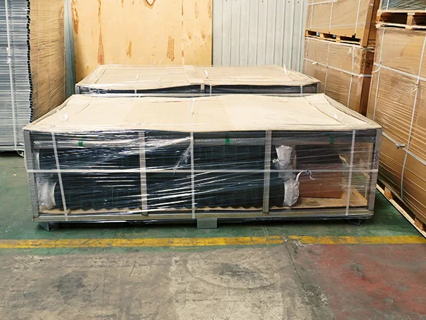 Two metal pallets of chain link sports fence on the ground.