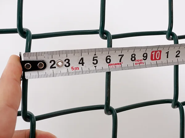 A QC worker is measuring the mesh size of chain link sports fence.