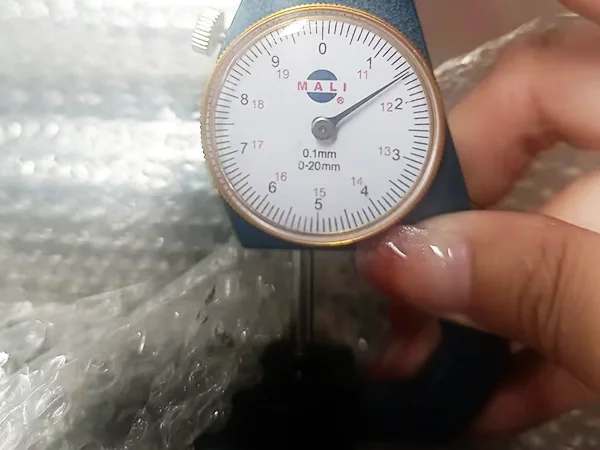 A QC worker is measuring the post thickness of chain link sports fence.