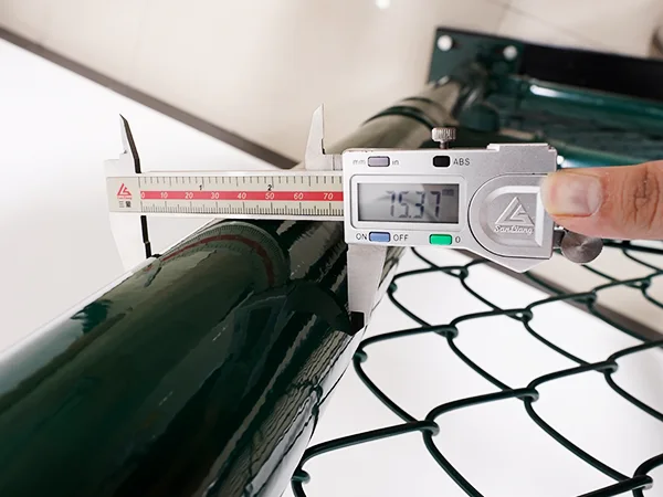 A QC worker is measuring the post size of chain link sports fence.
