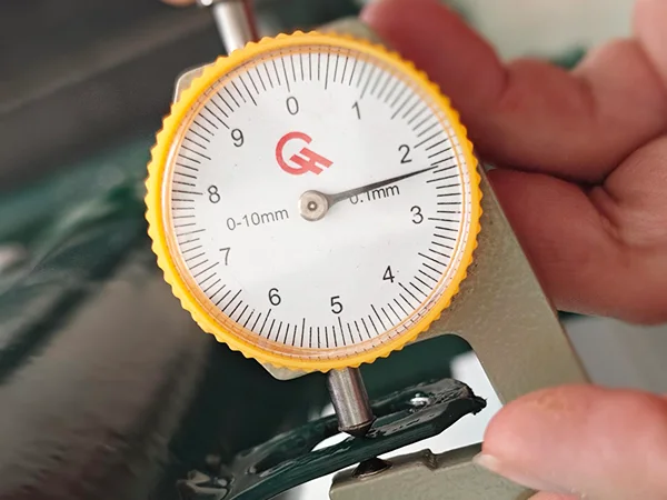 A QC worker is measuring the U clip thickness of chain link sports fence.