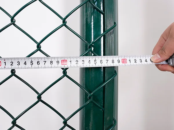 A QC worker is measuring the width of chain link sports fence.