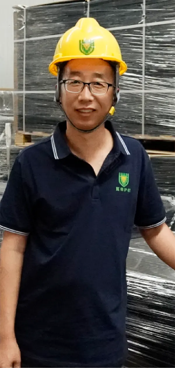 A worker is standing beside of the packed products with smile.
