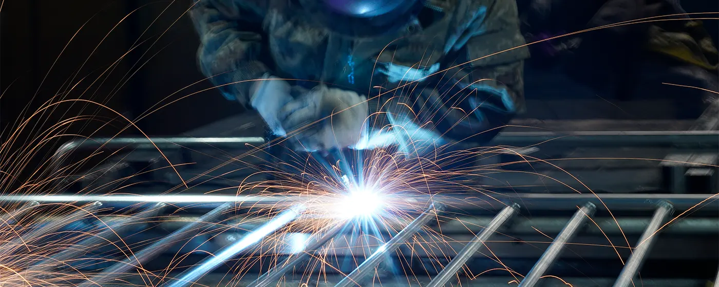 A worker is welding the vertical tubes on the frame.