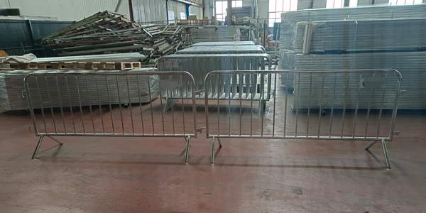 Two stainless steel crowd control barriers connected together inside factory workshop.